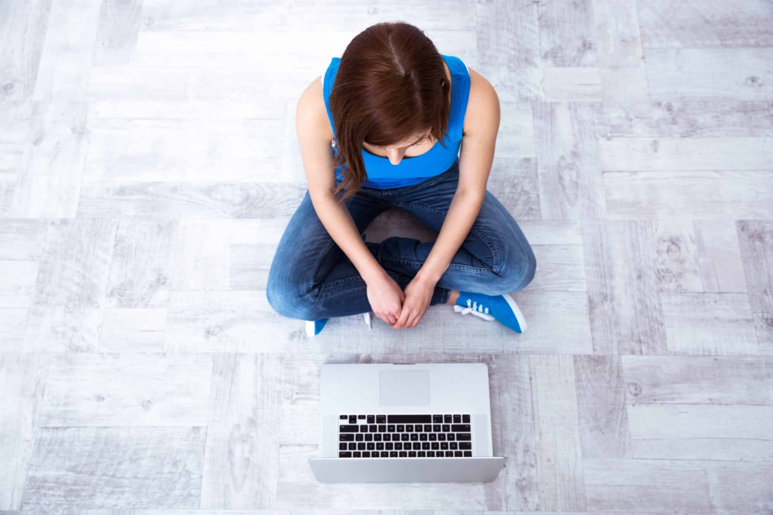 Top view portrait of a young woman sitting on floor with laptop